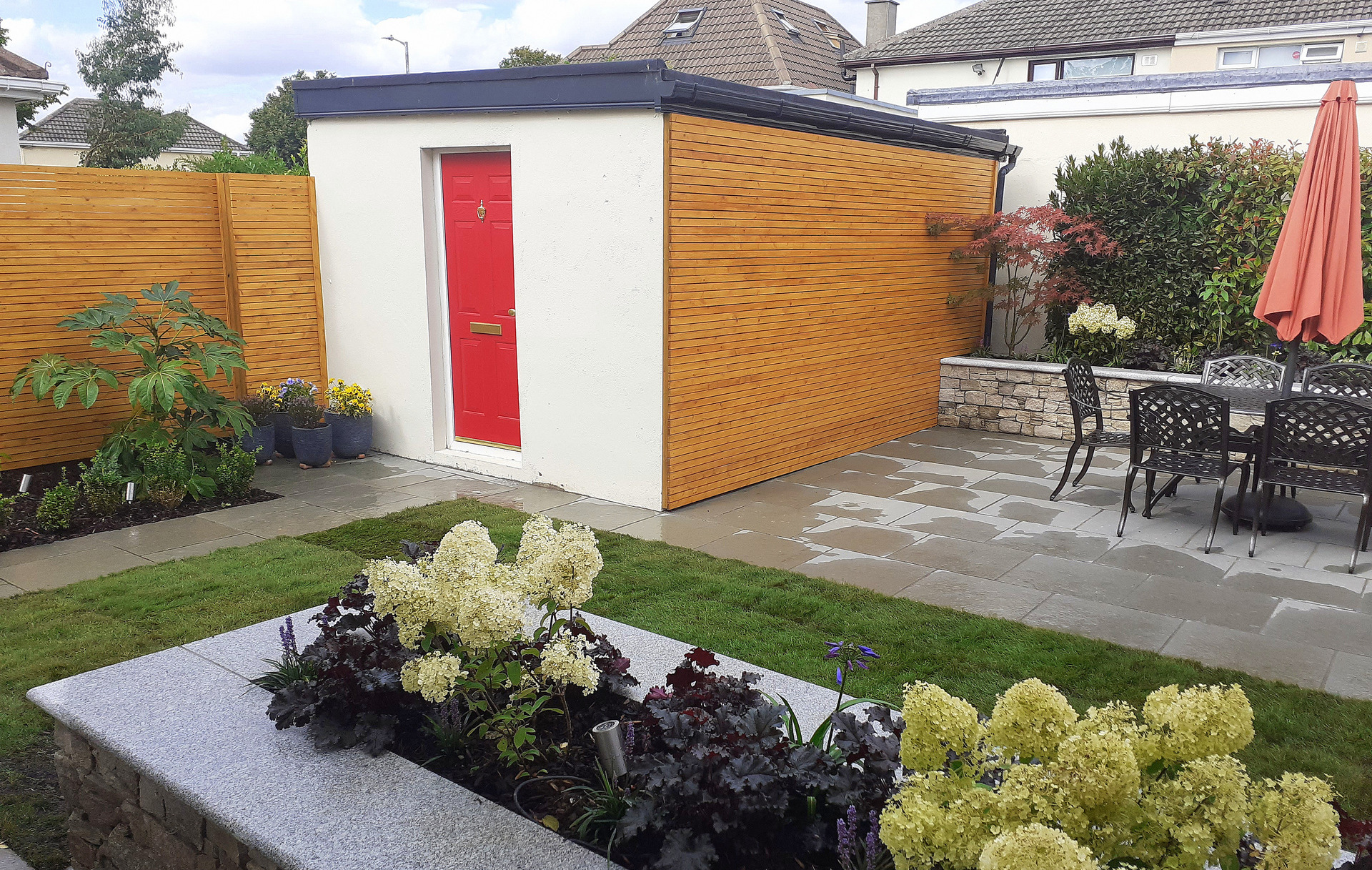 Family Garden Garden Design & Landscaping project in Firhouse, Dublin 24 featuring limestone patios, custom made horizontal slatted fencing, raised planter beds in natural stone, lush low maintenance planting & split level patios.