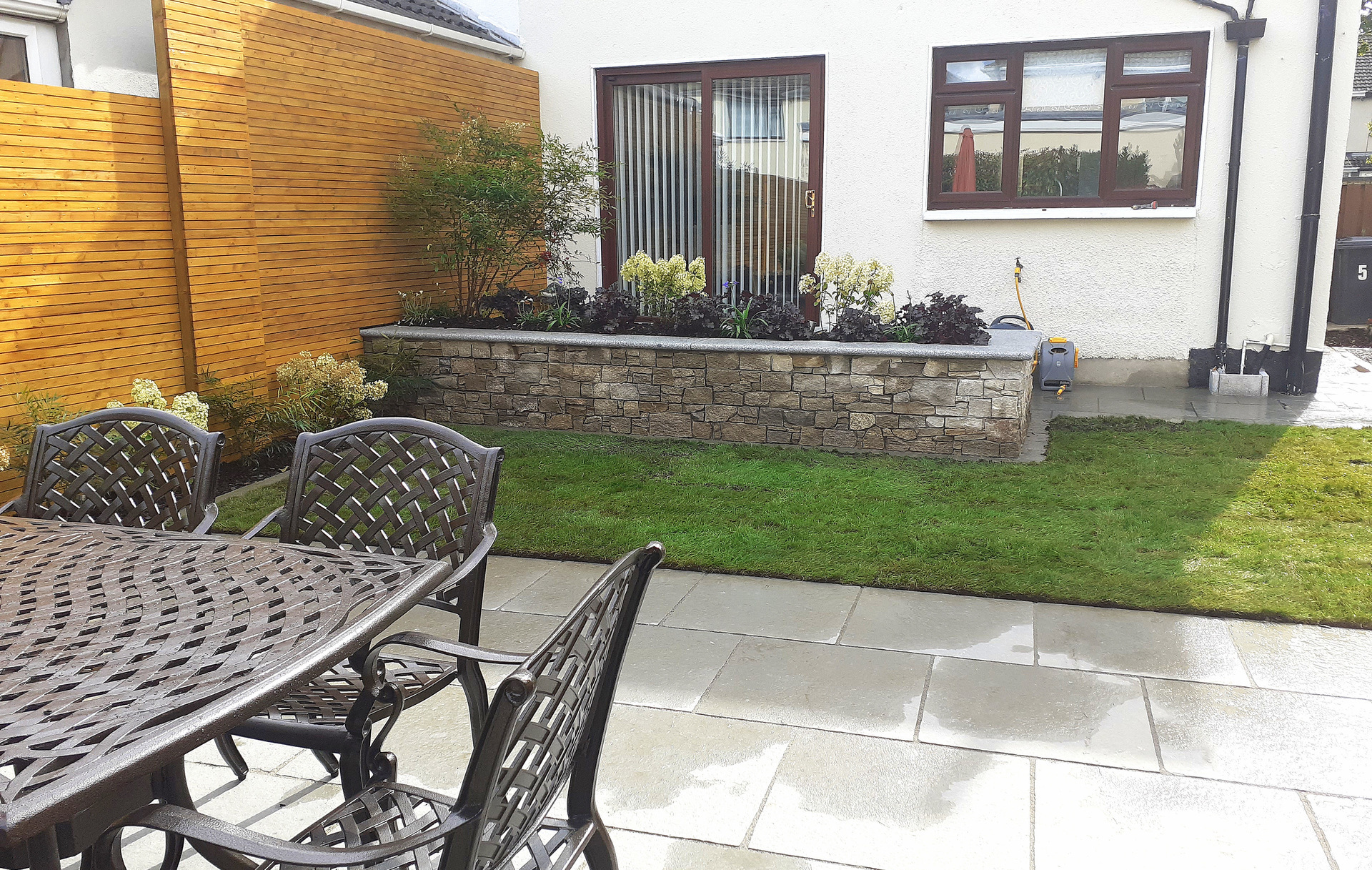 Family Garden Garden Design & Landscaping project in Firhouse, Dublin 24 featuring limestone patios, custom made horizontal slatted fencing, raised planter beds in natural stone, lush low maintenance planting & split level patios.