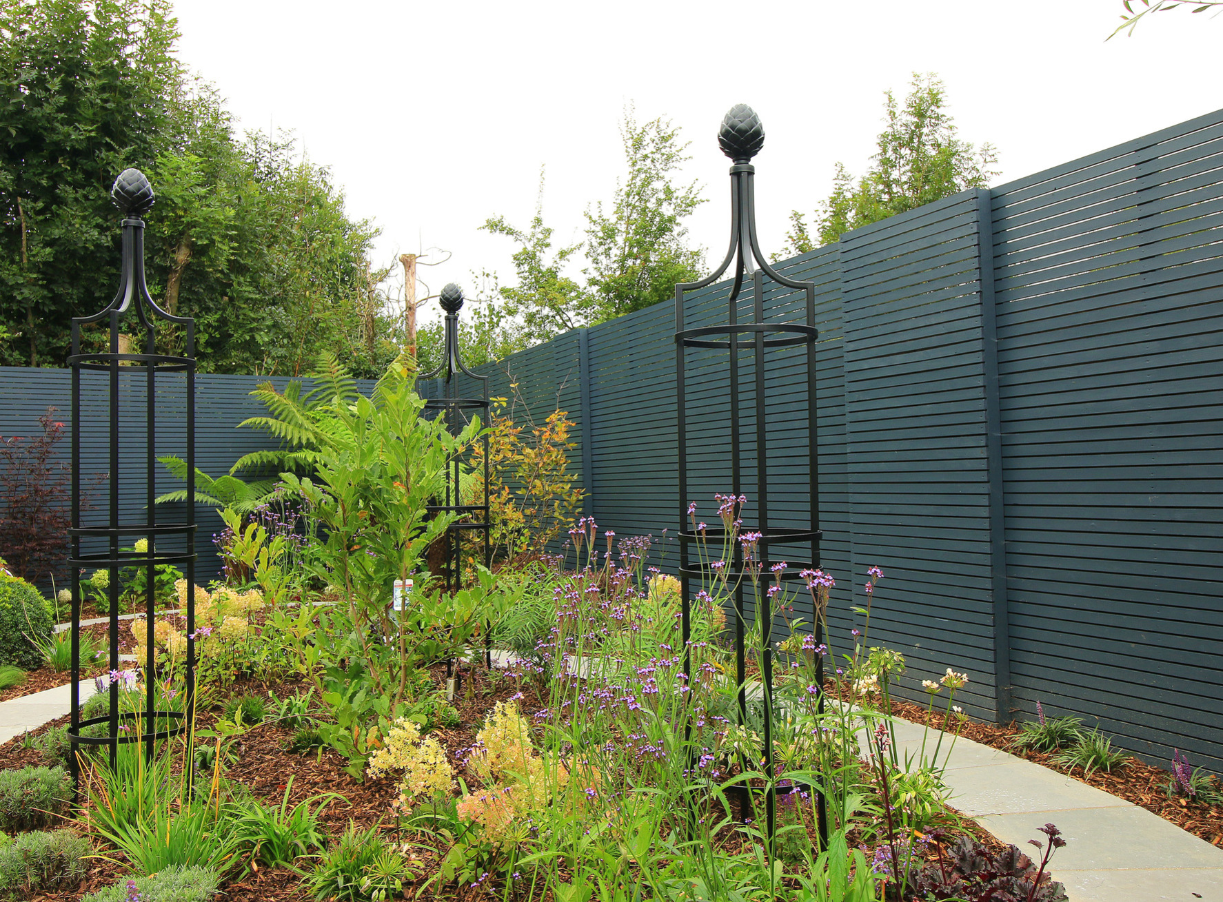 Stunning mixed planting scheme with custom horizontal slatted fencing & Classic Garden Element Obelisks