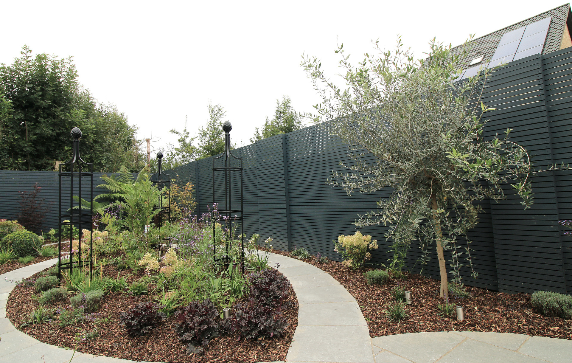 Family Garden Garden Design & Landscaping project in Rathcoole, Dublin 24 provides a host of visual features including Rose Obelisks by Classic Garden Elements, custom made horizontal timber slatted fencing, Limestone patios & paving | Design & Landscaping by Owen Chubb Garden Landscapers