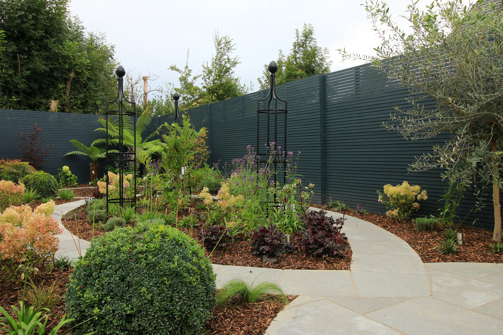 Family Garden Garden Design & Landscaping project in Rathcoole, Dublin 24 providing a host of visual features including specimen trees & shrubs, Rose Obelisks by Classic Garden Elements, custom made horizontal timber slatted fencing, Limestone patios & paving | Design & Landscaping by Owen Chubb Garden Landscapers