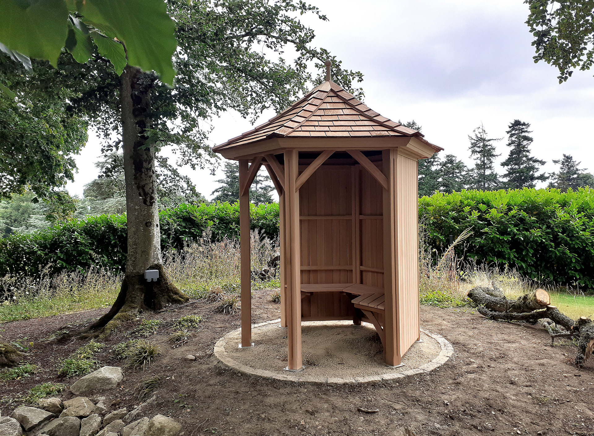 A stunning 1.8m six-sided Garden Gazebo by Victorian Garden Buildings, exceptionally well made in Western Red Cedar, with optional cedar bench. Supplied + Fitted by Owen Chubb Garden Landscapes Limited, in Maynooth, Co Kildare.